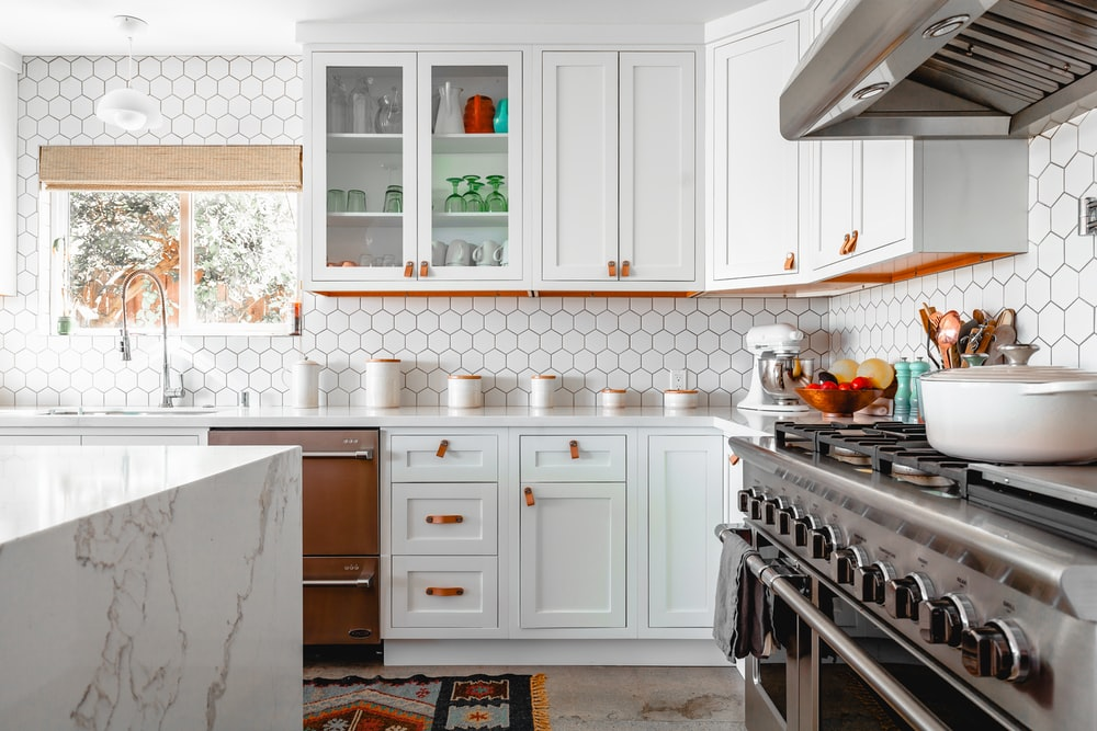 a white kitchen with a marble island and a gas stove