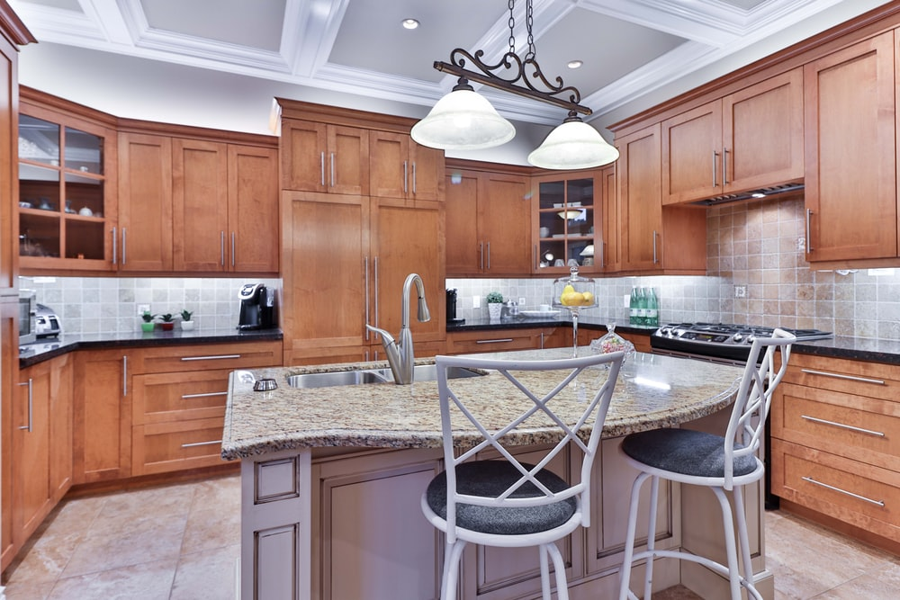  traditional dark brown wooden cabinets paired with a brown granite island and black countertops